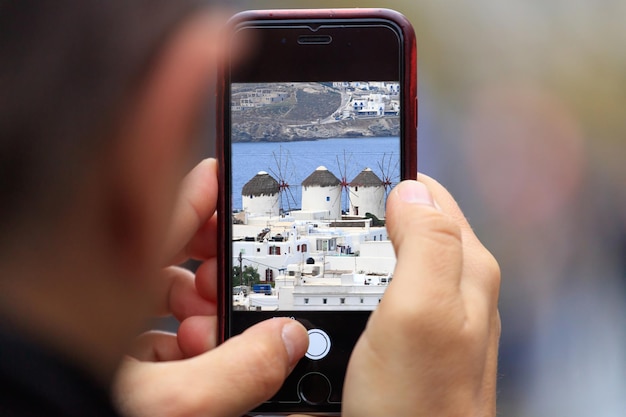 Mykonos island picture appears on tablet smartphone in man's hands Blurred background