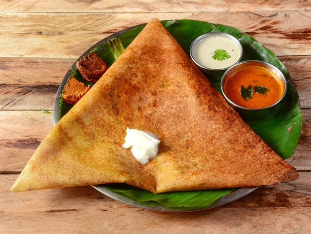 Mysore Masala dosa a famous south Indian traditional breakfast with filling of a mixture of mashed potatoes served with different chutney and sambar over a rustic wooden background selective focus