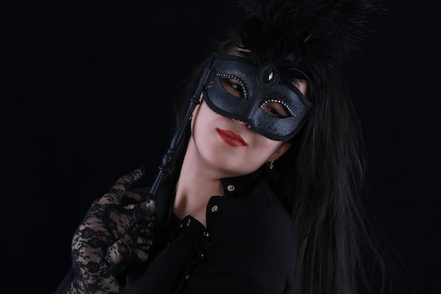 mysterious beautiful girl in a black venetian mask on a black background