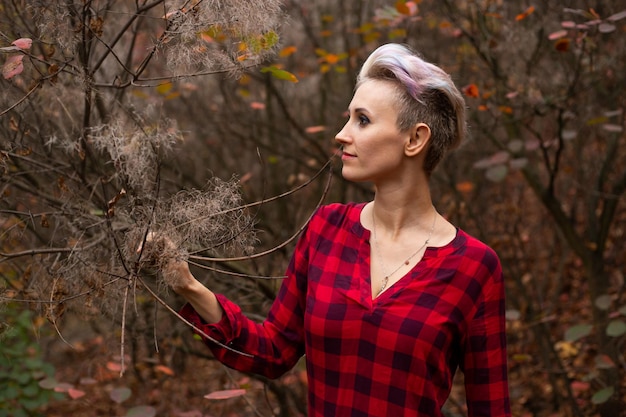 Mysterious woman with short hair in autumn forest background with withered trees