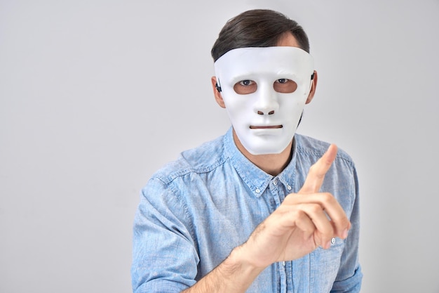 Mystery man in white mask on his face isolated on studio background