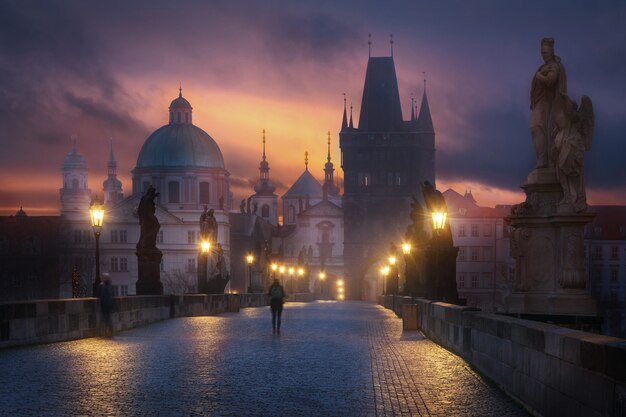 Mystic charles bridge at night with a tourist in the foreground