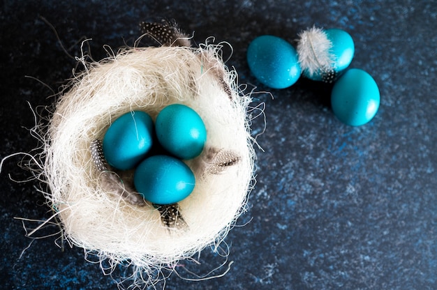 Mystical coloring Easter eggs with twigs in a decorative nest on blue