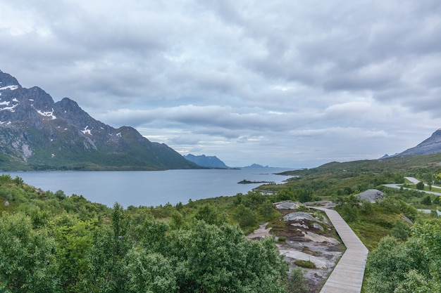 A mystical fjord in Norway with mountains and fog hanging over the water in polar day