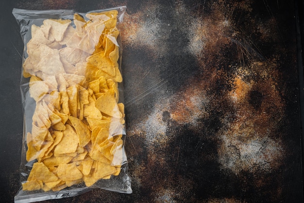 Nachos, corn tortilla in bag, on old dark rustic table, top view or flat lay