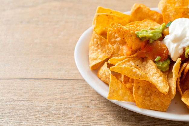 Nachos tortilla chips with jalapeno guacamole tomatoes salsa and dip