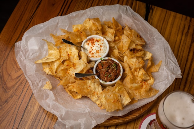 Nachos with sauces on plates on a wooden table