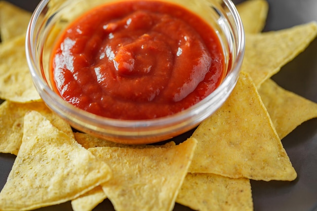 Nachos with tomato salsa on dark gray plate selective focus