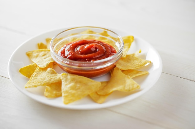 Nachos with tomato salsa on a white plate selective focus