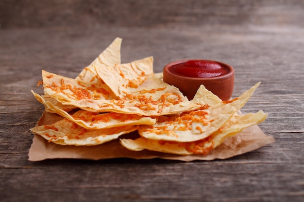 Nachos with tomato sauce on a dark  wooden background. Mexican food concept, nachos.