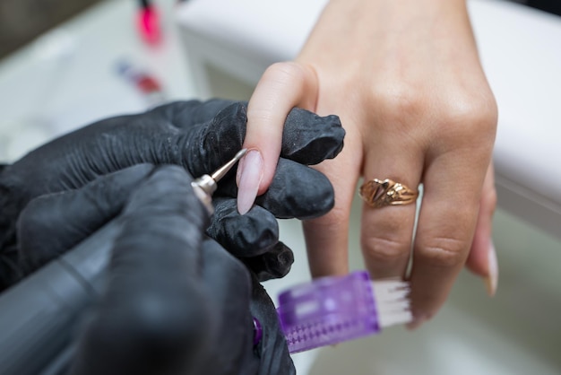 Nail care concept Manicurist makes a manicure to a client girl in a beauty salon