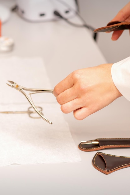 Nail nippers in the hand of female manicure master putting to the towel before nail care in manicure salon.