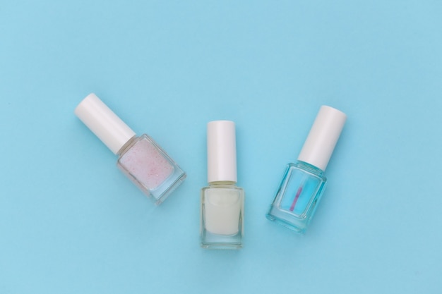 Nail polish bottle on blue background. Beauty concept. Top view