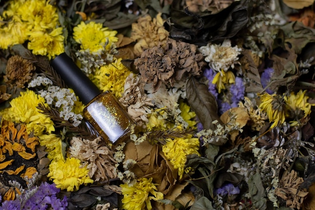 Photo nail polish gold and glitter shiny reflective placed amongst assorted dried flowers