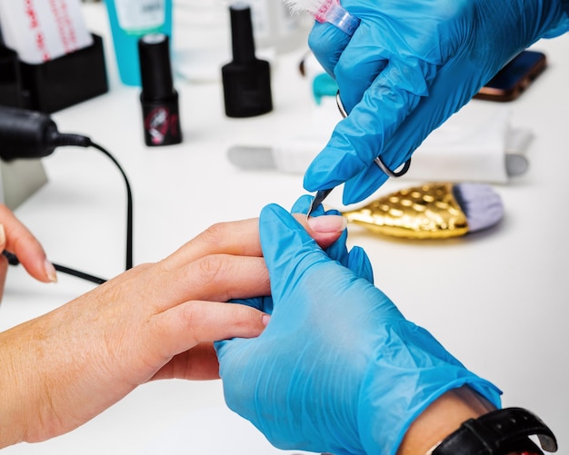 Nail salon. Cuticle removal with manicure scissors. Close-up shot