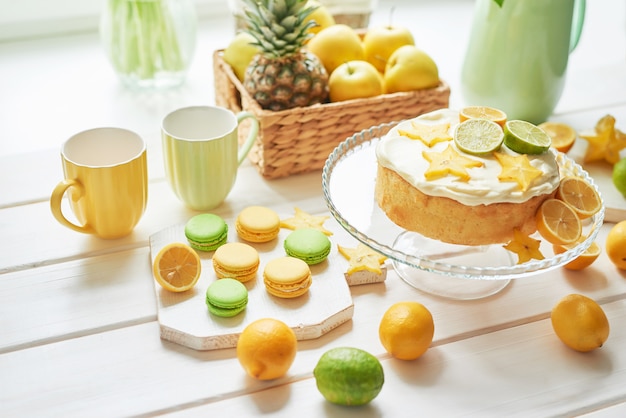 Naked cake with lemons and limes, fruits, sweet macarons and white tulips