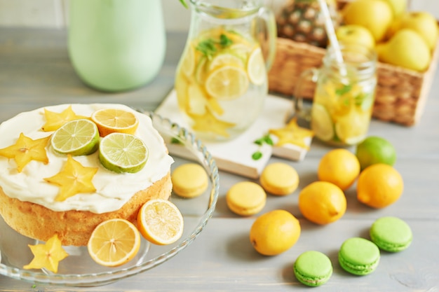 Naked cake with lemons and limes, lemonade, fruits and sweet macarons