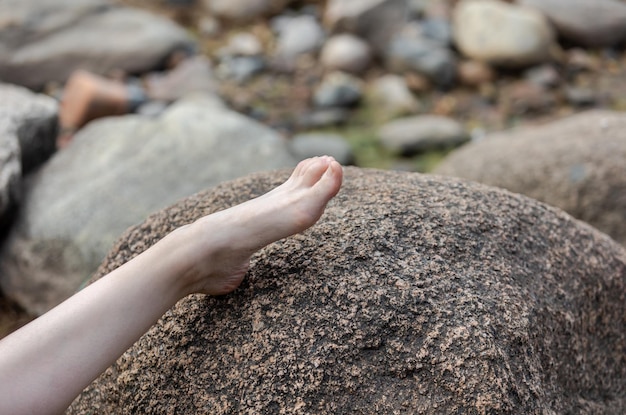 Naked female leg lies on a large stone