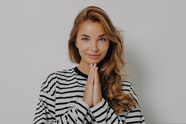 Namaste pleased attractive young woman keeps palms pressed together says thank you