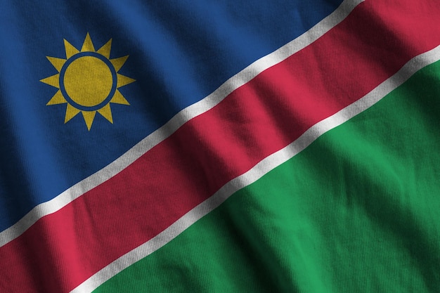 Namibia flag with big folds waving close up under the studio light indoors The official symbols and colors in banner