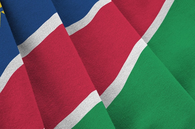 Namibia flag with big folds waving close up under the studio light indoors The official symbols and colors in banner