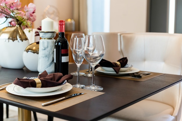 Napkins on a plates with wine glasses and bottle red wine on table.