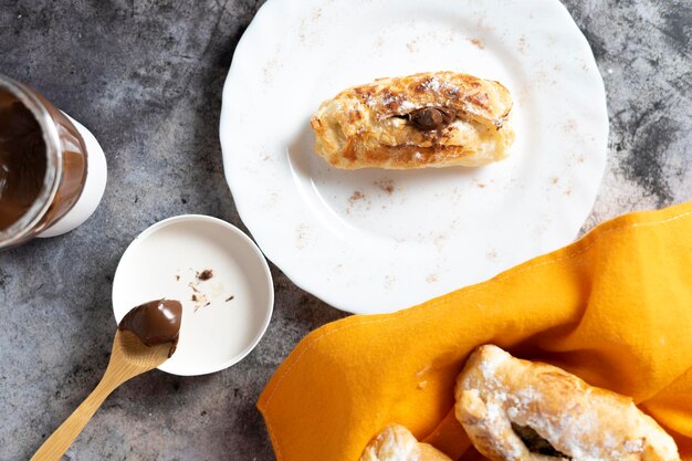 Napolitana pastry filled with chocolate with basket, coffee cup, jar and spoon with chocolate