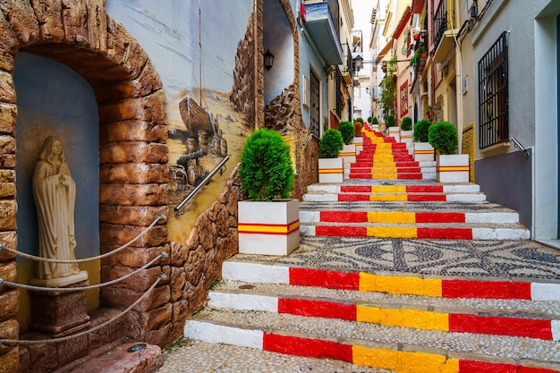 Narrow alley decorated with the flag of Spain on the steps. Calpe Alicante.