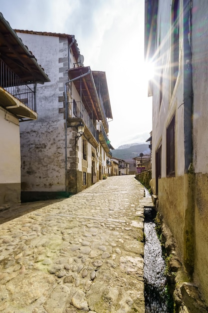 Narrow alley of old houses with water channel that goes down the street from the mountain Candelario Salamanca