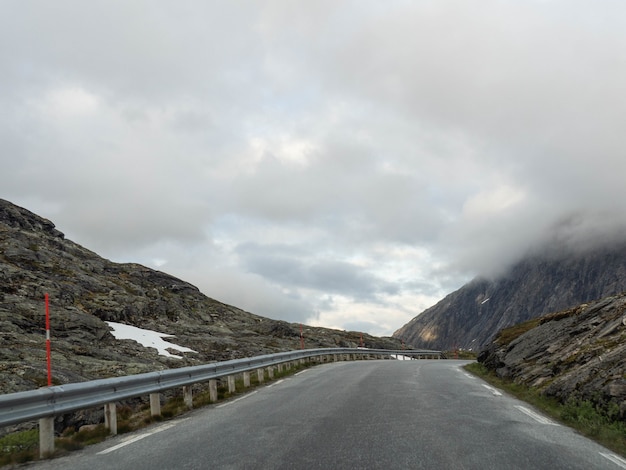 Narrow asphalt road high in the mountains on a gray cloudy day