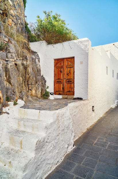 Narrow steep streets with houses white walls and blooming bushes and old stairs in old town Lindos