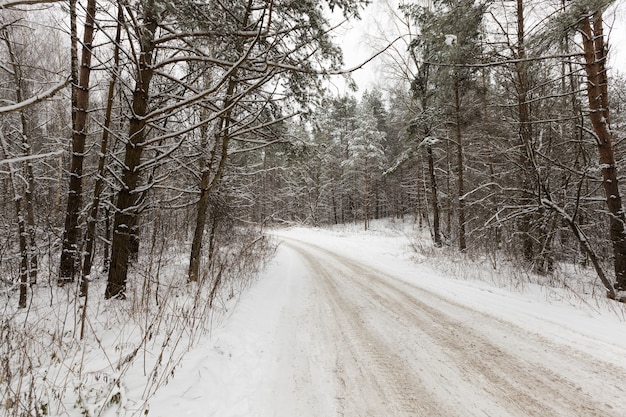 Narrow unpaved snowcovered winter road for car traffic