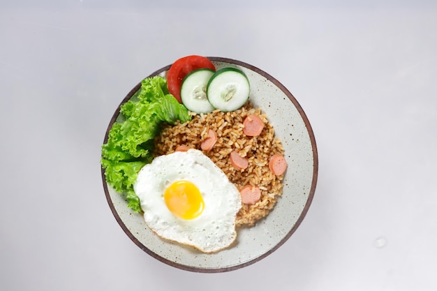 Nasi Goreng Sosis is Fried Rice with Sausages garnished with fresh cucumber and tomatoes slices.