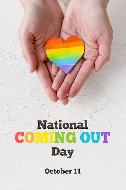 Photo national coming out day stop homophobia heart with rainbow lgbt flag in hands on white background