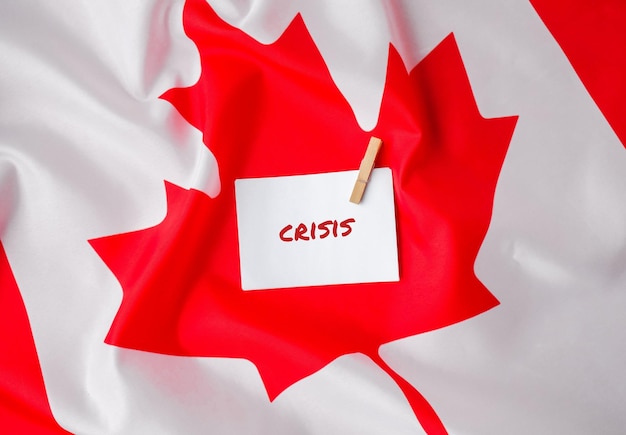 The National Flag of Canada Canadian Flag with the Maple Leaf and paper note message text CRISIS