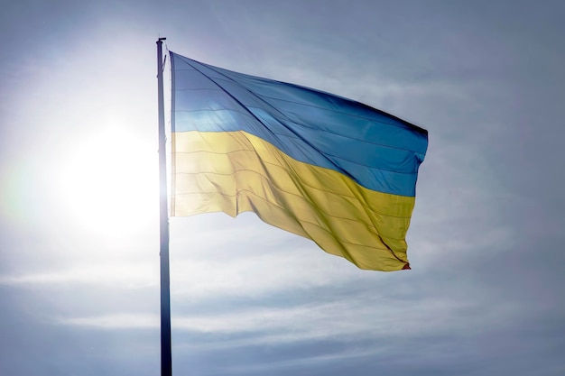 The national flag of the country of Ukraine against the background of the sun and blue sky Patriotism and national symbol