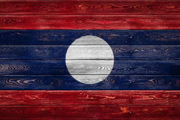 The national flag of Laos is painted on a camp of even boards nailed with a nail. The symbol of the country.