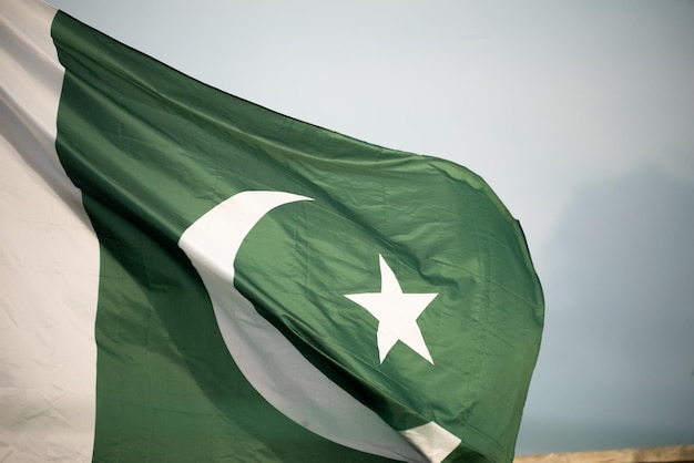 The national flag of Pakistan flying in the blue sky with clouds