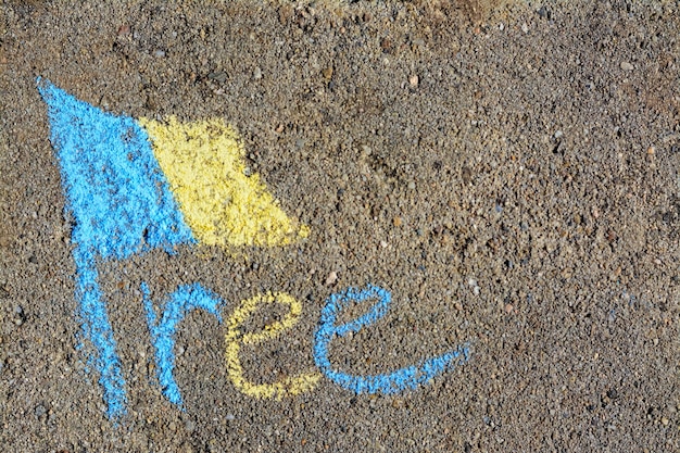 National flag of Ukraine with word Free drawn by blue and yellow chalk on asphalt top view