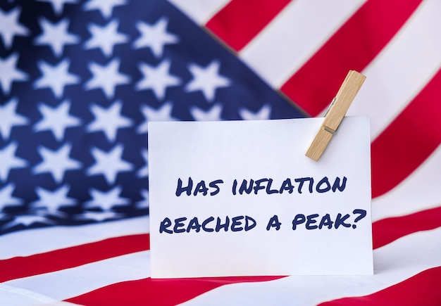 The National Flag of USA American Flag and paper note message text HAS INFLATION REACHED A PEAK