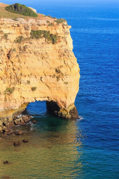 Natural arch in cliff Summer Atlantic rocky coast view near beach Praia da Afurada Lagoa Algarve Portugal