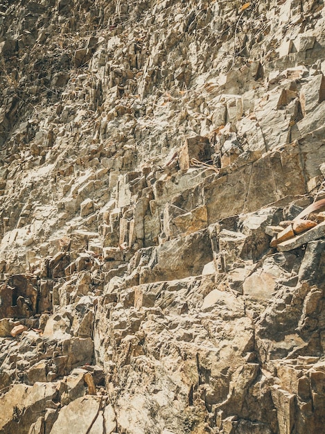 Natural background Closeup edged shabby cliff cracks Graybrown stone rock texture of mountains Vintage and faded matt style colour in tinted photo Concept of geolog mountaineering or hard work