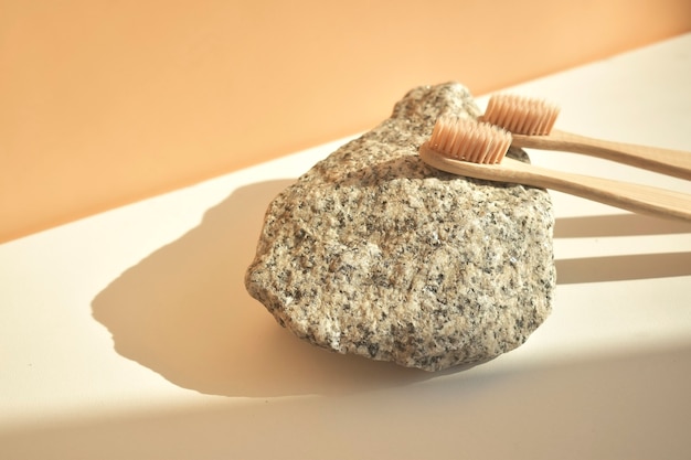 Natural bamboo toothbrush on a white background with a decor of natural stone and flowers. Plastic free Essentials, dental care. The concept of zero waste.