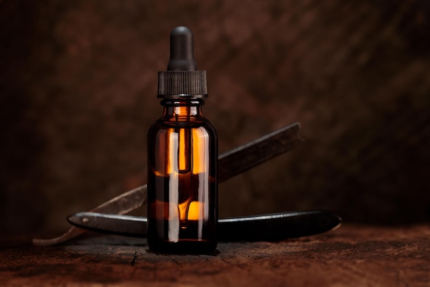 Natural beard care product, bottle and razor on old wood background. Presentation of product.