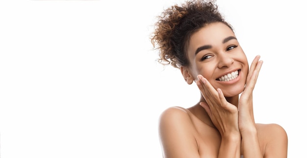 Natural beauty. Beautiful girl holding her cheeks, laughing and looking aside over white background