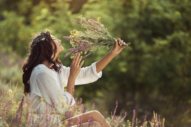 Natural Beauty Girl with Bouquet of Flowers Outdoor in Freedom Enjoyment Concept.