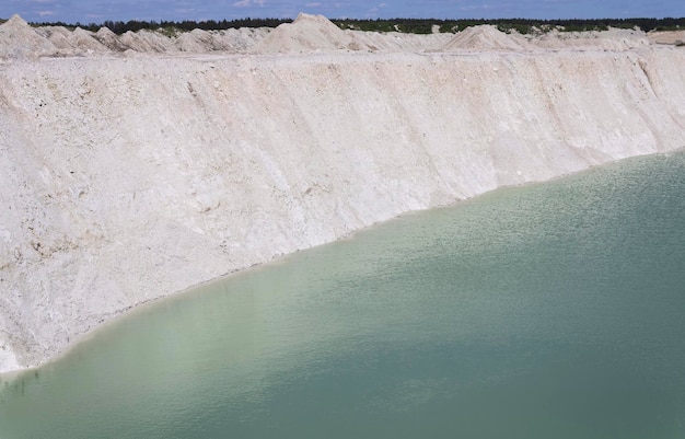 Natural blue water in an active chalk quarry with steep banks and blue sky