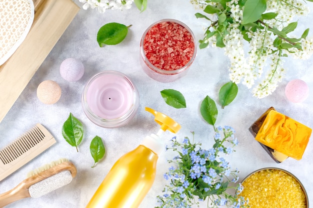 Natural body care products and accessories lay out with flowers and leaves