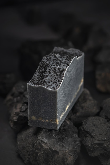 Natural charcoal soap on real coals on a black background Concept of making and using organic eco soap and cosmetics