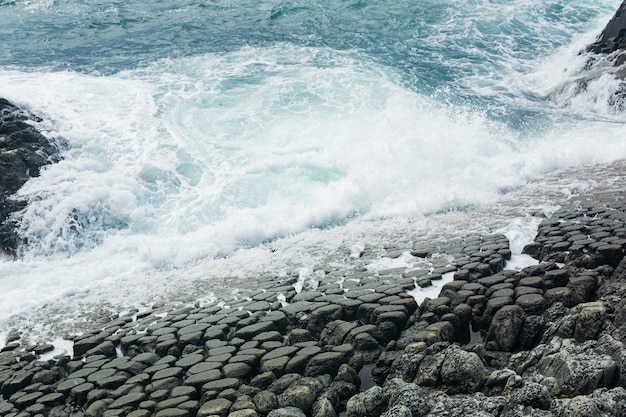 Natural cobblestone causeway formed by the ends of lava columns descends into the sea surf